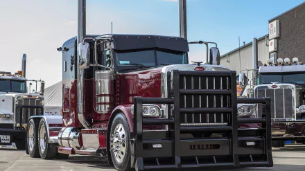 HD PC desktop wallpaper featuring a maroon Peterbilt truck parked in an industrial area with clear skies in the background.