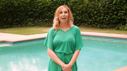 HD desktop wallpaper featuring celebrity Kari Byron smiling and standing in front of a pool with lush greenery in the background.