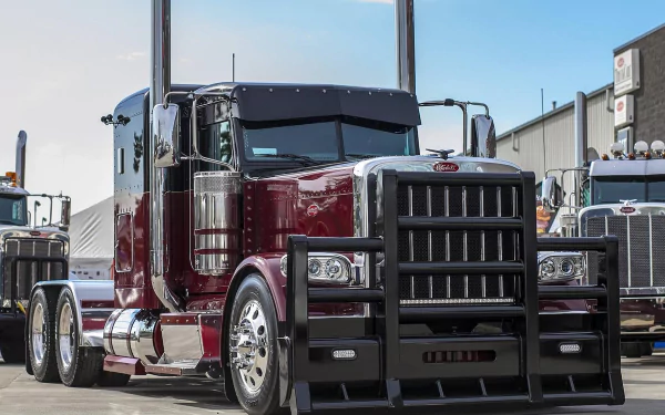 HD PC desktop wallpaper featuring a maroon Peterbilt truck parked in an industrial area with clear skies in the background.