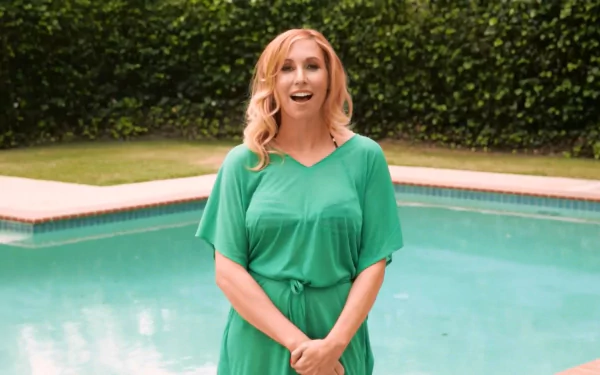 HD desktop wallpaper featuring celebrity Kari Byron smiling and standing in front of a pool with lush greenery in the background.
