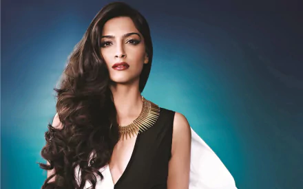 Stunning HD wallpaper of Bollywood actress and model with brunette hair, Sonam Kapoor, exuding elegance in a sophisticated black and white outfit against a dark blue-green background.