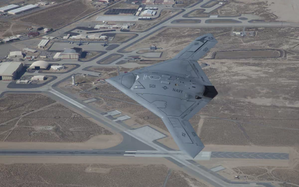 Aerial view of the Northrop Grumman X-47B military drone flying over an airbase, captured in HD for a desktop wallpaper and background.
