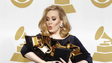 Adele, the renowned British singer, poses with multiple Grammy Awards, showcasing her musical achievements against a backdrop of iconic Grammy logos. HD desktop wallpaper.