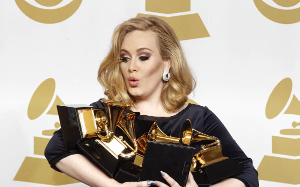 Adele, the renowned British singer, poses with multiple Grammy Awards, showcasing her musical achievements against a backdrop of iconic Grammy logos. HD desktop wallpaper.