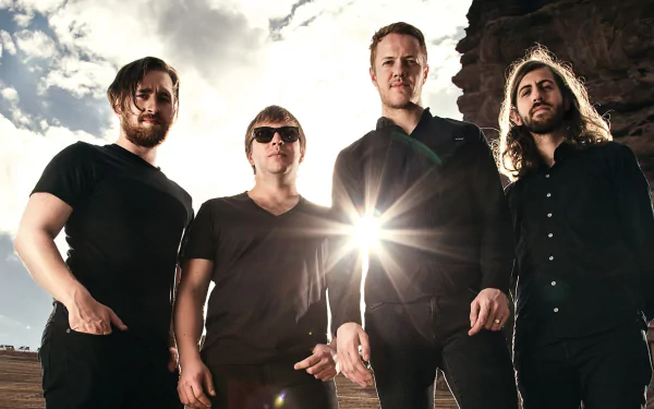 An HD wallpaper featuring the American alternative band Imagine Dragons, with band members standing confidently against a dramatic sky, radiating energy and creativity.