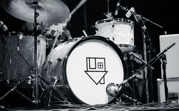 A close-up of a drum kit featuring a bass drum with a logo, representing the American alternative band Imagine Dragons, set against a dark concert backdrop in 4K Ultra HD.