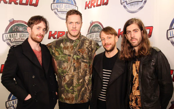 A group of four members of the American alternative band Imagine Dragons poses for a photo at a KROQ event, showcasing their unique styles and camaraderie.
