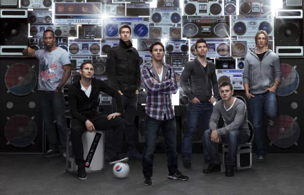 A dynamic HD wallpaper featuring soccer stars Fernando Torres, Jack Wilshere, Sergio Agüero, Lionel Messi, Frank Lampard, and Didier Drogba posed against a vibrant backdrop of vintage speakers.