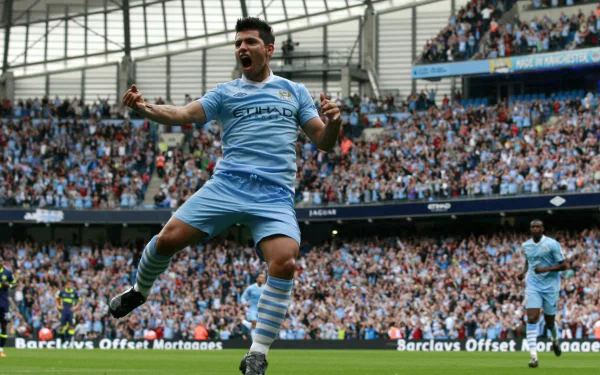 Sergio Agüero celebrates a goal for Manchester City F.C. in a vibrant stadium filled with cheering fans, capturing the spirit of iconic sports moments in this HD wallpaper.