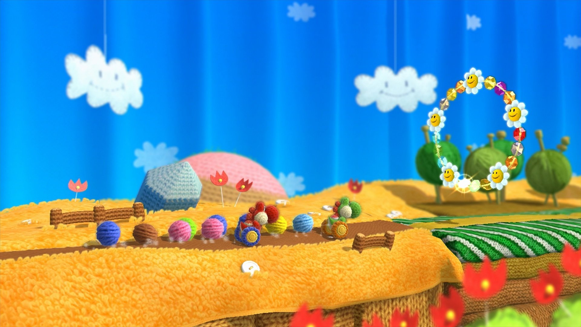 HD desktop wallpaper from Yoshi's Woolly World showcasing a vibrant, yarn-themed landscape with colorful decorations and a blue sky backdrop.