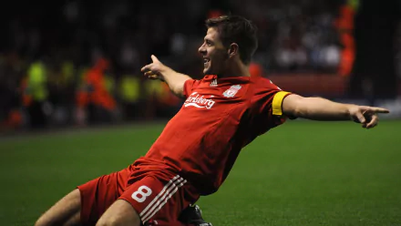 Midfielder in red Liverpool kit sliding in celebration on the pitch — sports action 2K Quad HD PC desktop wallpaper.