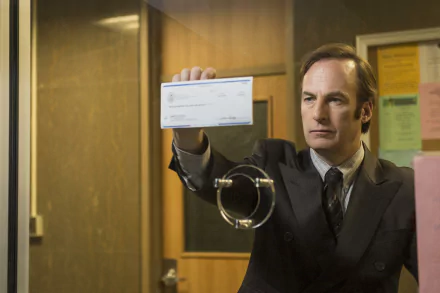 Bob Odenkirk as Jimmy McGill holding up a check in a scene from Better Call Saul, a perfect wallpaper for fans of the show.