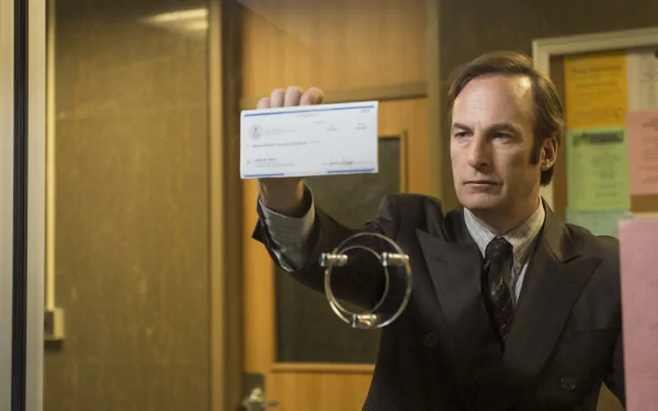 Bob Odenkirk as Jimmy McGill holding up a check in a scene from Better Call Saul, a perfect wallpaper for fans of the show.