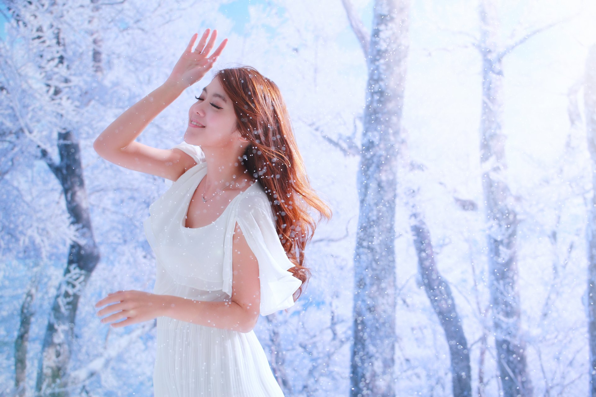 A Taiwanese woman in a white dress smiles amidst a snowy, winter forest. The image is tagged with Qiān Yòu and serves as an HD desktop wallpaper and background.