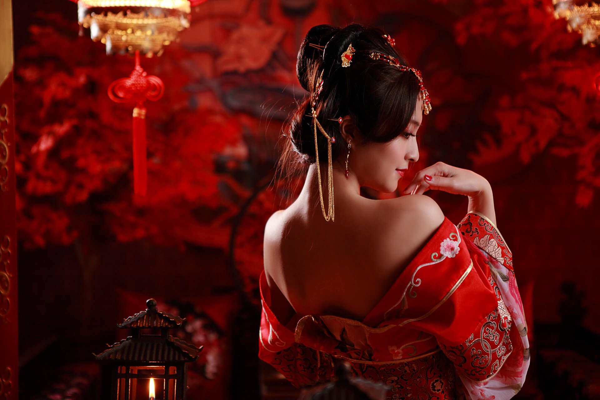 A woman in traditional Taiwanese dress elegantly poses against a rich red background, adorned with candles and decorative elements, highlighting her intricate hairstyle and cultural attire.