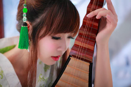 Asian Taiwanese woman in national dress, face close to a lute-like instrument as she plays — serene musician portrait, 5K Ultra HD desktop wallpaper.