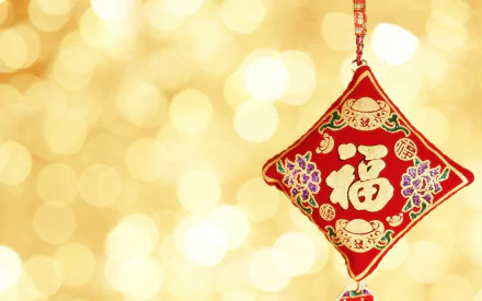 HD PC desktop wallpaper featuring a red Chinese New Year hanging ornament with gold characters and floral designs against a sparkling golden bokeh background.