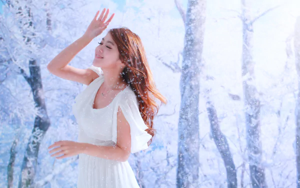 A Taiwanese woman in a white dress smiles amidst a snowy, winter forest. The image is tagged with Qiān Yòu and serves as an HD desktop wallpaper and background.