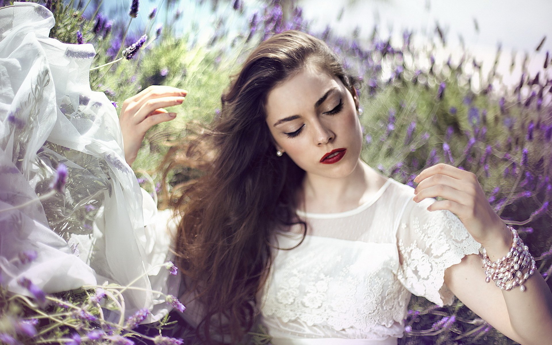 HD desktop wallpaper of a serene bride in a white lace dress surrounded by lavender flowers, with flowing hair and a calm, contemplative expression.