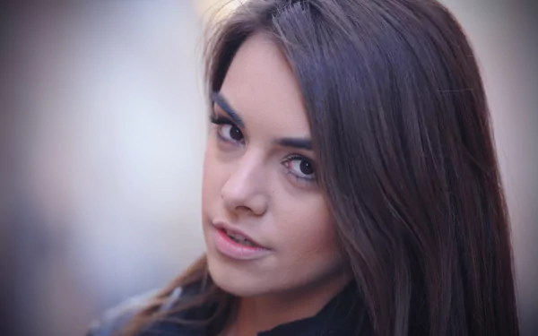 Close-up portrait of a woman with long dark hair and expressive eyes by Anita Sikorska, rendered in 4K Ultra HD for PC desktop wallpaper and background.