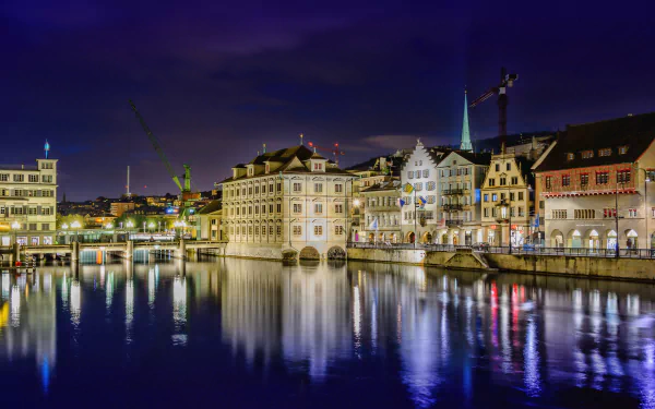 Nighttime cityscape of Zurich with illuminated historic buildings reflecting on calm water, captured in a high-definition man-made environment for PC desktop wallpaper.