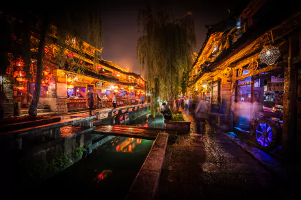 Night view of a vibrant shopping area in Lijiang, Yunnan, China with illuminated streets and traditional architecture, suitable as a HD desktop wallpaper.