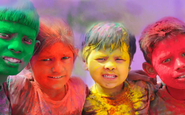 A vibrant HD wallpaper featuring children celebrating Holi, adorned with colorful powders in shades of red, yellow, and green, capturing the joy of the holiday.