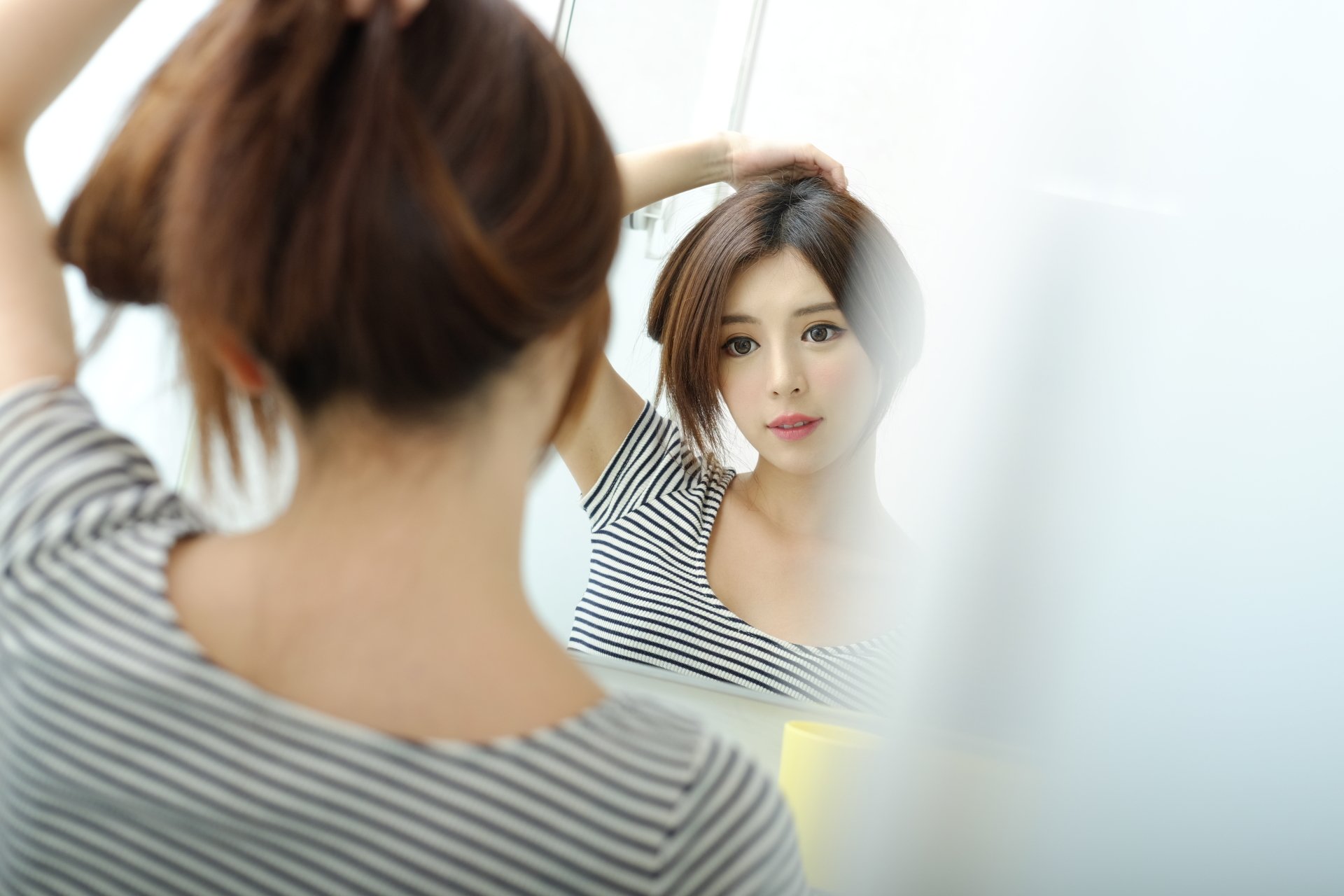 4K Ultra HD desktop wallpaper: Taiwanese Asian woman adjusting her hair as she gazes at her face in a mirror, soft-lit reflective portrait for a PC background.