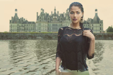 A woman model poses confidently near the water with the Château de Chambord in France as the backdrop in this HD desktop wallpaper.