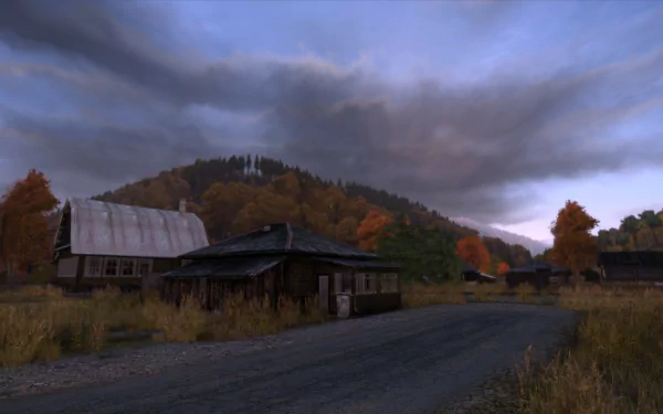 HD PC desktop wallpaper from the video game Arma 2: DayZ Mod: an abandoned rural village by a gravel road, autumn trees, moody overcast sky and a wooded hill in the distance.