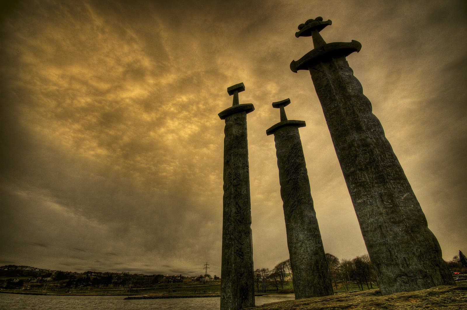 Three towering swords stand proudly in the Stavanger Swords Monument, silhouetted against a dramatic sky, creating a striking and historic atmosphere in this HD desktop wallpaper.