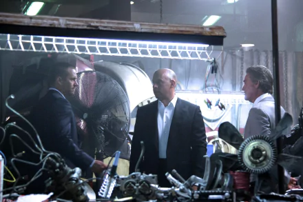 HD wallpaper featuring Vin Diesel as Dominic Toretto in a scene from Furious 7, showcasing intense dialogue amidst a backdrop of mechanical parts.