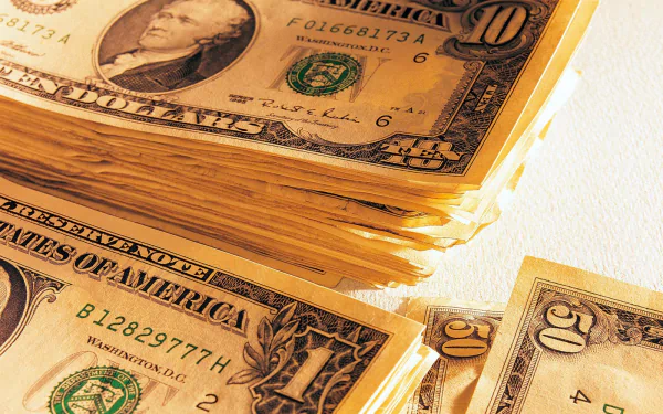 Close-up of neatly stacked U.S. dollar bills, showcasing various denominations against a clean background. HD PC desktop wallpaper featuring a man-made currency theme.