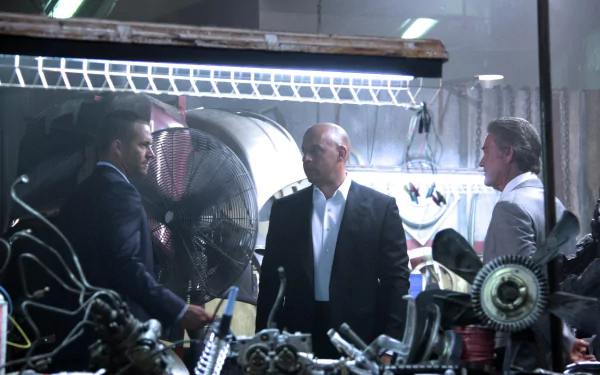 HD wallpaper featuring Vin Diesel as Dominic Toretto in a scene from Furious 7, showcasing intense dialogue amidst a backdrop of mechanical parts.