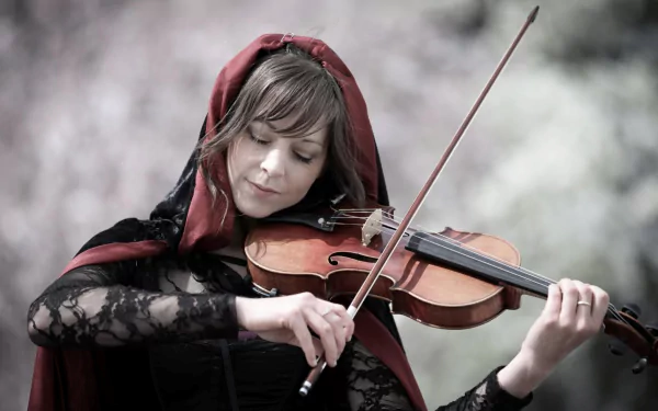 HD desktop wallpaper featuring Lindsey Stirling playing the violin, dressed in a dark lace outfit with a red hood, set against a blurred natural background.