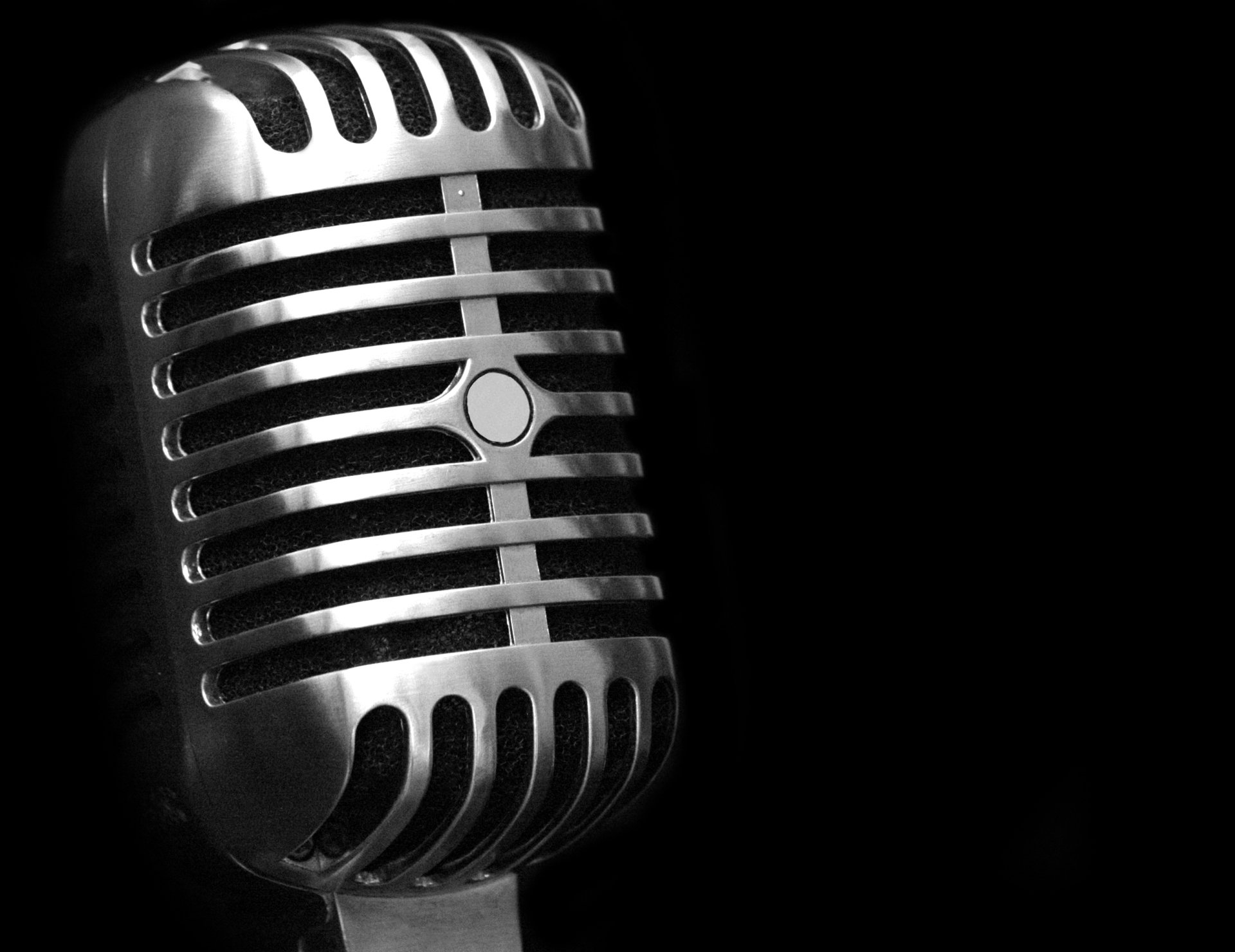 A striking close-up of a vintage microphone against a black background, capturing the essence of music and sound. This HD desktop wallpaper adds a stylish touch to any screen.