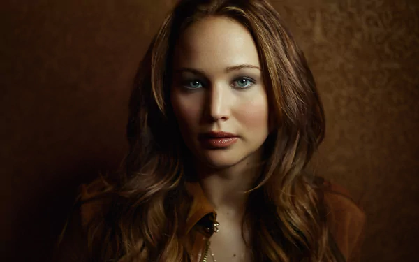 High-definition wallpaper featuring Jennifer Lawrence, showcasing her captivating expression against a warm brown background.