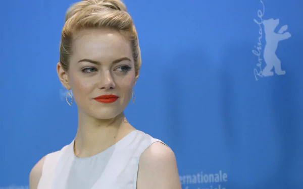 Emma Stone poses gracefully against a blue backdrop, showcasing her elegant style. This 4K Ultra HD image serves as a stunning PC desktop wallpaper.