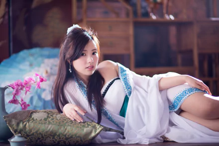 An HD desktop wallpaper featuring Taiwanese model Chén Sīyǐng lounging on a cushion with an orchid in the background, showcasing a serene and elegant ambiance.