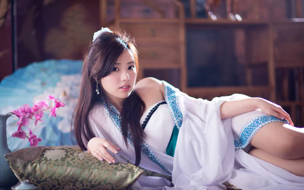 An HD desktop wallpaper featuring Taiwanese model Chén Sīyǐng lounging on a cushion with an orchid in the background, showcasing a serene and elegant ambiance.