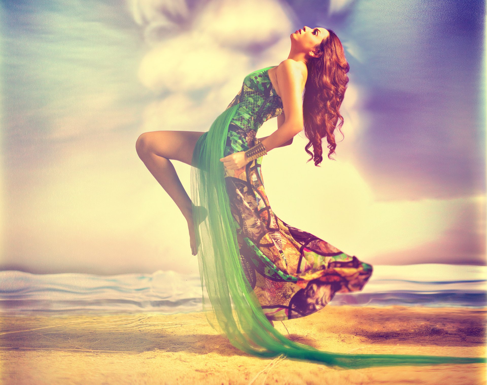 2K Quad HD desktop wallpaper showing an Indian woman in a flowing green dress leaping on a sunlit beach, warm pastel sky and gentle waves in the background.