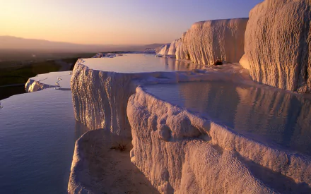 HD desktop wallpaper showcasing the natural terraces of Pamukkale at sunset, with cascading pools and warm light highlighting the unique geological formations.