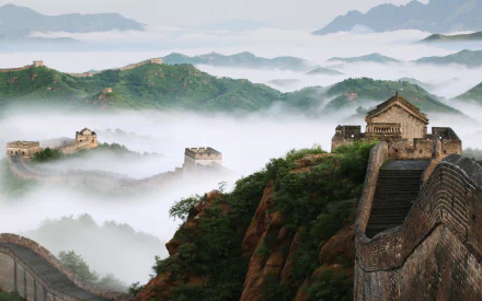 A breathtaking view of the Great Wall of China shrouded in mist, showcasing the incredible man-made structure against a backdrop of lush green hills and a serene sky.