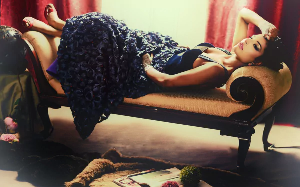 Indian woman model reclining on a vintage sofa in a textured evening dress, moody studio lighting — 2K Quad HD PC desktop wallpaper/background.