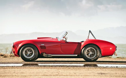 Red Shelby Cobra muscle car parked on a desert road, showcased as an HD PC desktop wallpaper and background featuring the iconic AC Cobra design.