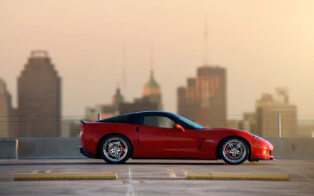 Red Chevrolet Corvette Z06 parked on rooftop with city skyline background, shown in sharp HD for PC desktop wallpaper and background.