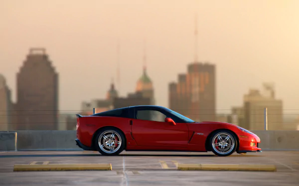 Red Chevrolet Corvette Z06 parked on rooftop with city skyline background, shown in sharp HD for PC desktop wallpaper and background.
