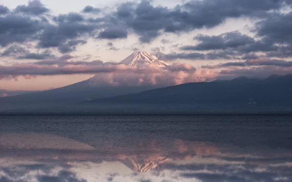 5K Ultra HD desktop wallpaper of Mount Fuji volcano in Shizuoka Prefecture at sunrise, cloud-wreathed peak reflected on calm water — nature scene, Japan.
