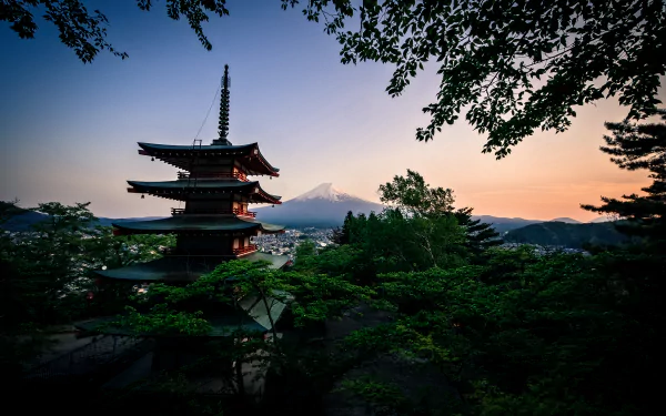 A stunning view of a traditional pagoda surrounded by lush nature, with Mount Fuji rising majestically in the background during sunset, showcasing Japan's serene beauty.