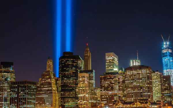 A stunning HD wallpaper showcasing the Manhattan skyline at night, illuminated by powerful beams of light against a backdrop of vibrant city lights, capturing the essence of New York.